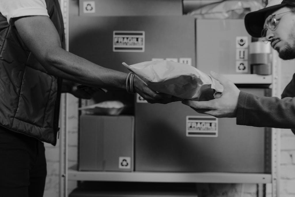 A delivery person hands a package to a client in an organized logistics center.