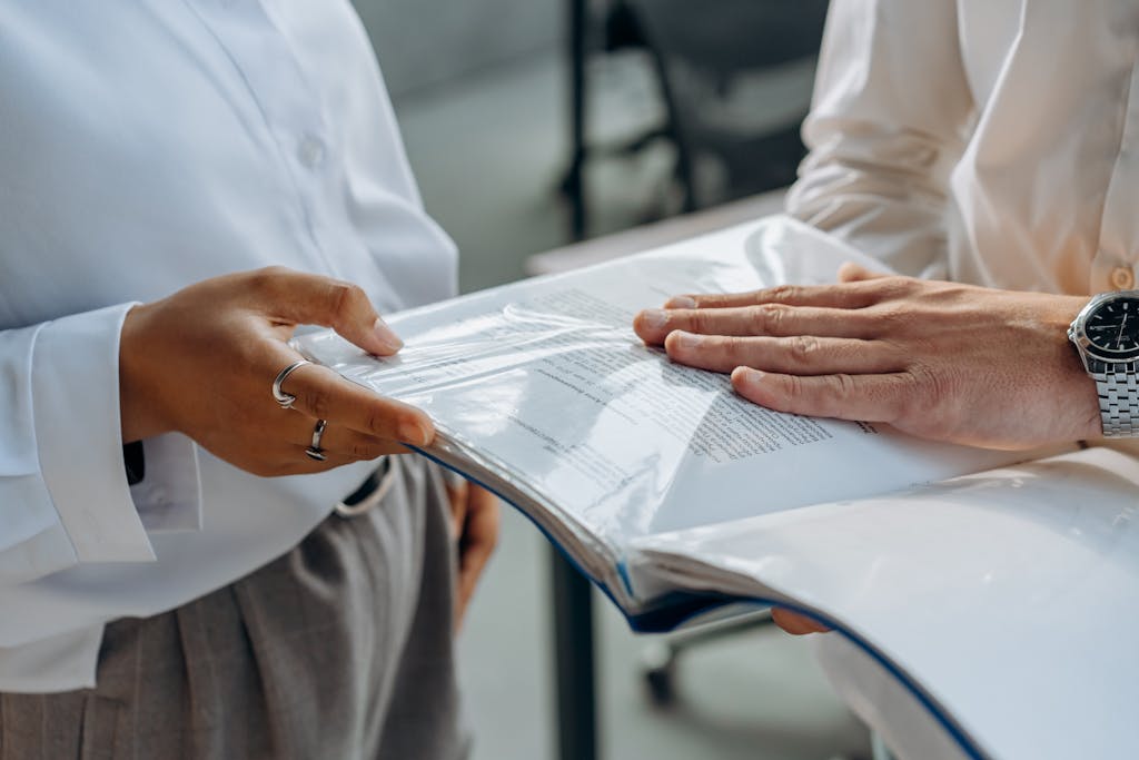 Two professionals examining business documents during a meeting indoors.